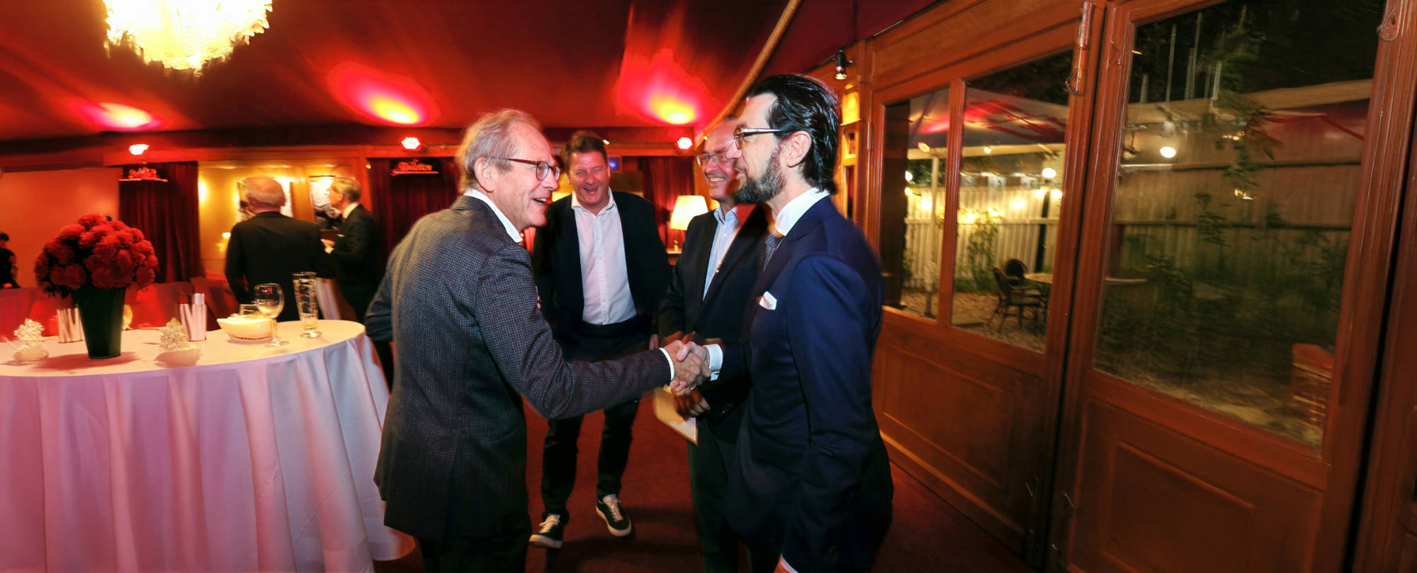 Business-Event mit Gästen im Gespräch und Handschlag in abendlicher Location – Eventfotografie für Unternehmen in Berlin