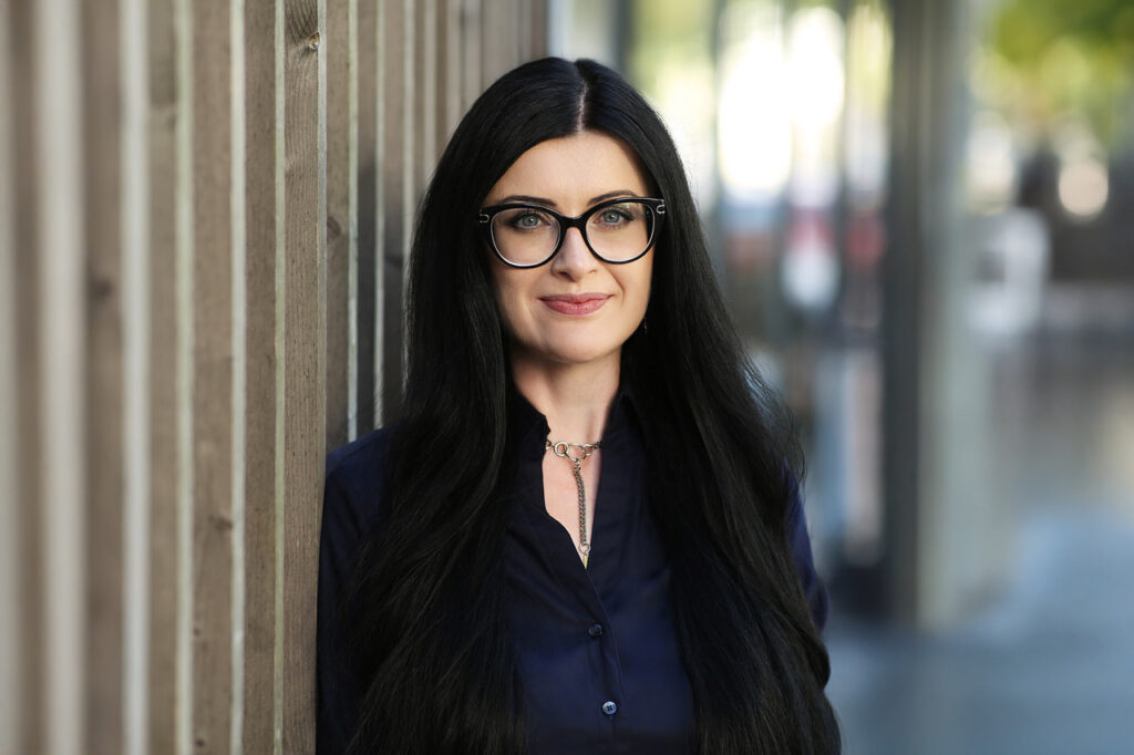 Professionelles Portrait einer Frau mit Brille vor moderner Holz- und Glasfassade