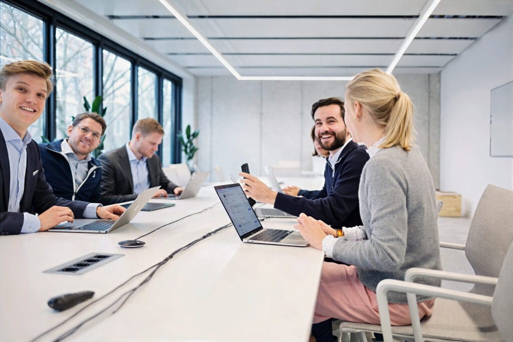 Teammeeting im modernen Büro mit mehreren Mitarbeitenden am Tisch – Mitarbeiterfotos für Unternehmen in Berlin