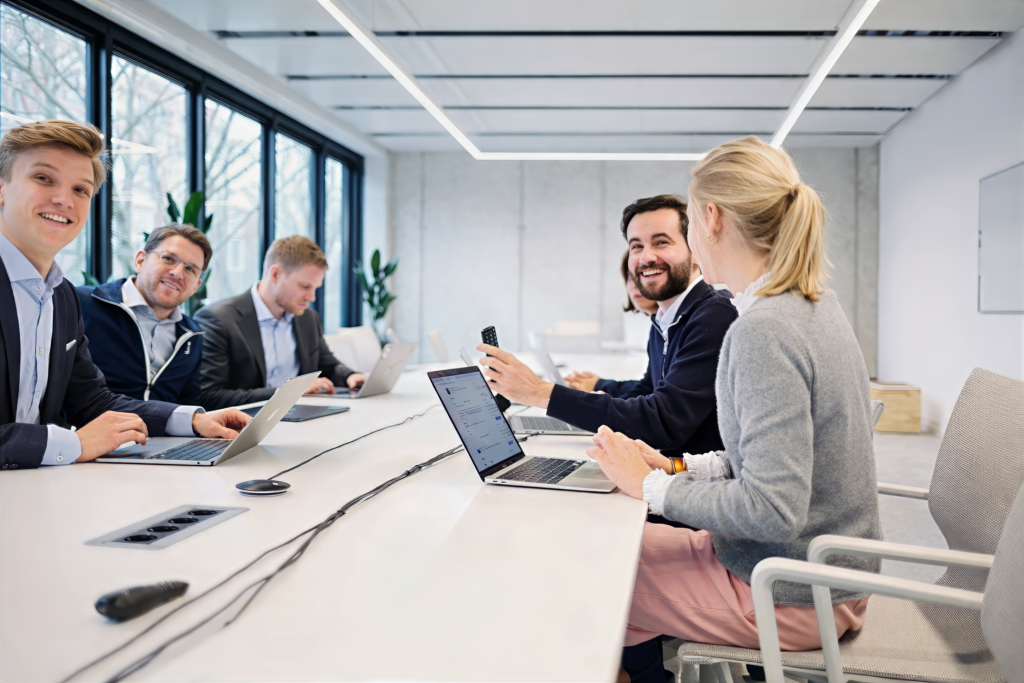 Teammeeting im modernen Büro mit mehreren Mitarbeitenden am Tisch – Mitarbeiterfotos für Unternehmen in Berlin