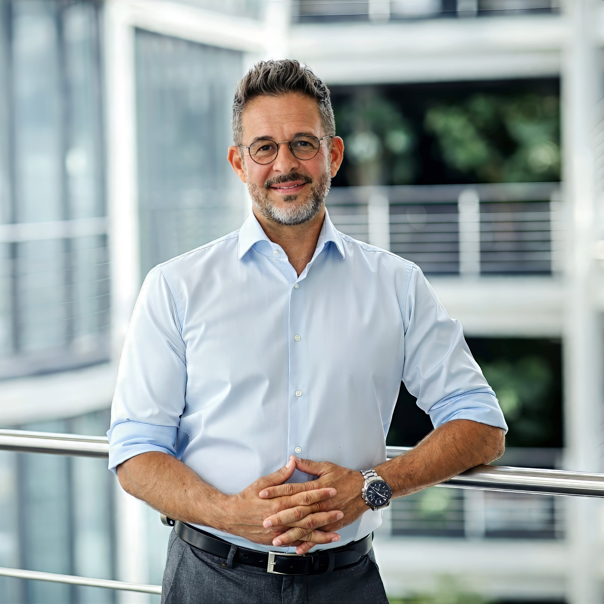Businessportrait eines Mannes im hellblauen Hemd vor Glasfassade – Unternehmensfotos in Berlin