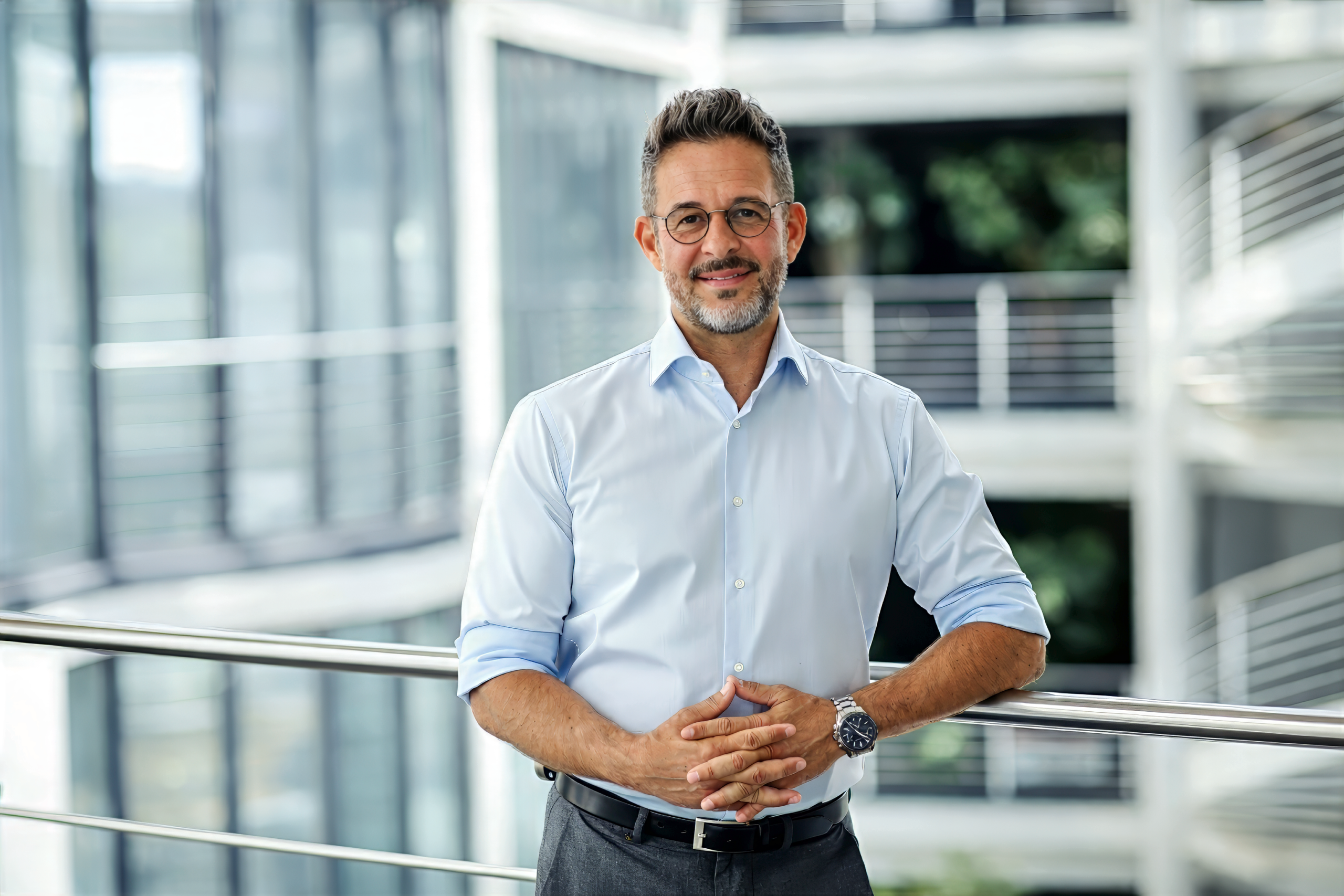 Businessporträt eines Mitarbeiters im Hemd vor Glasfassade – professionelles Mitarbeiterfoto Berlin