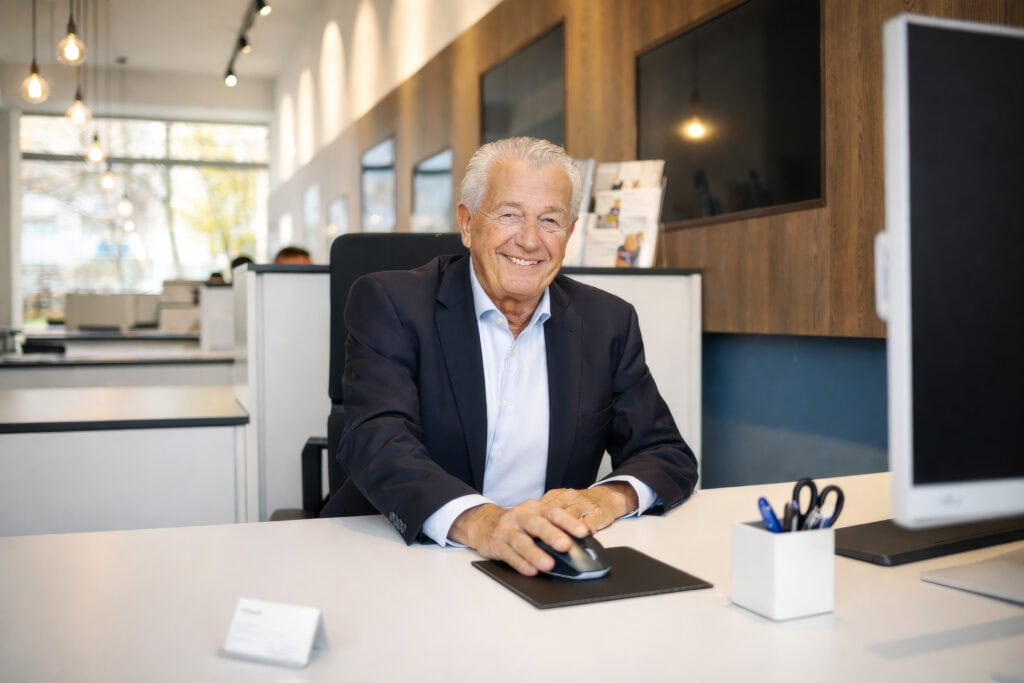 Mitarbeiterfoto eines Mannes am Schreibtisch im offenen Büro – Businessporträt am Arbeitsplatz