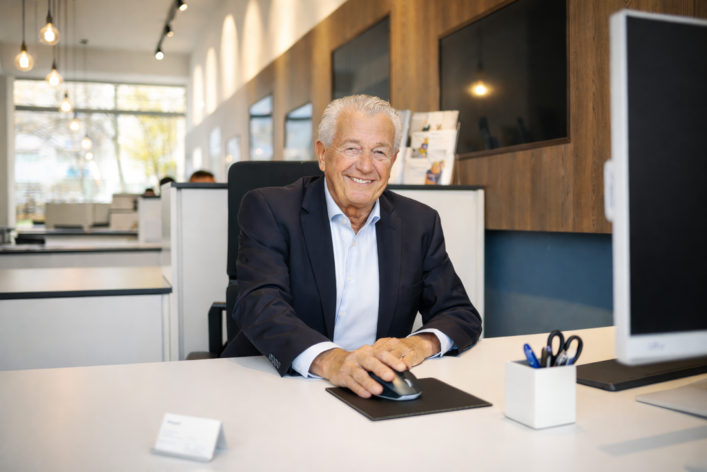 Mitarbeiterfoto eines Mannes am Schreibtisch im offenen Büro – Businessporträt am Arbeitsplatz