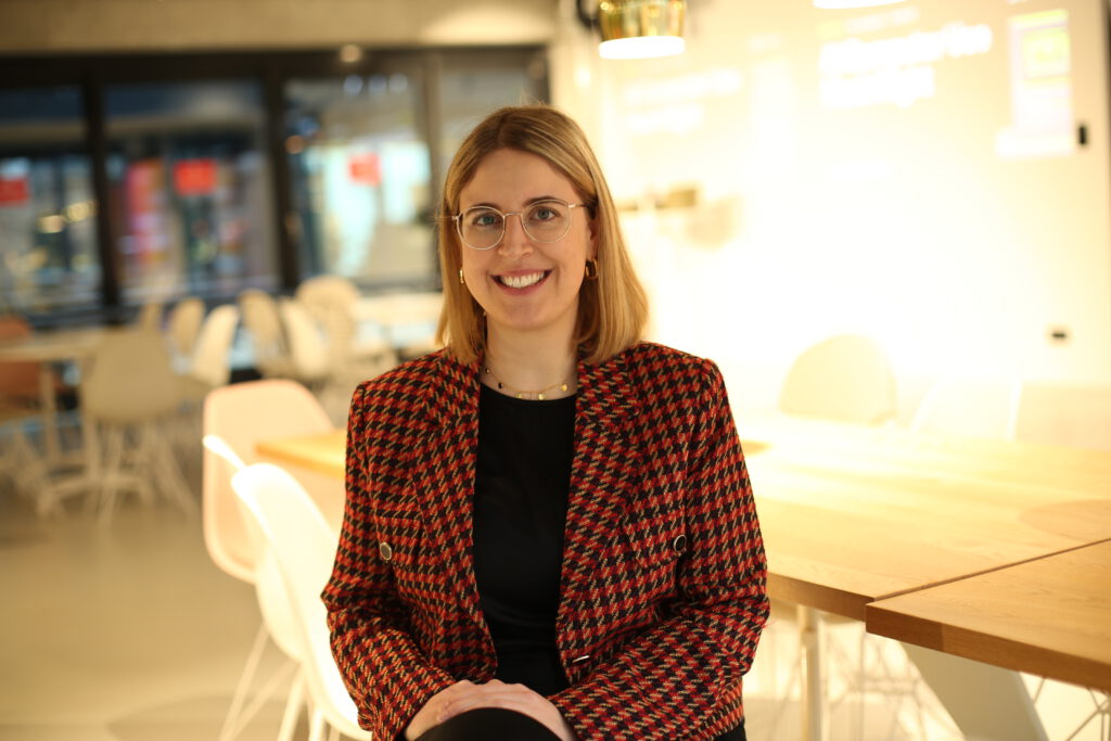 Businessportrait einer Frau mit Brille im gemusterten Blazer in modernem Innenraum